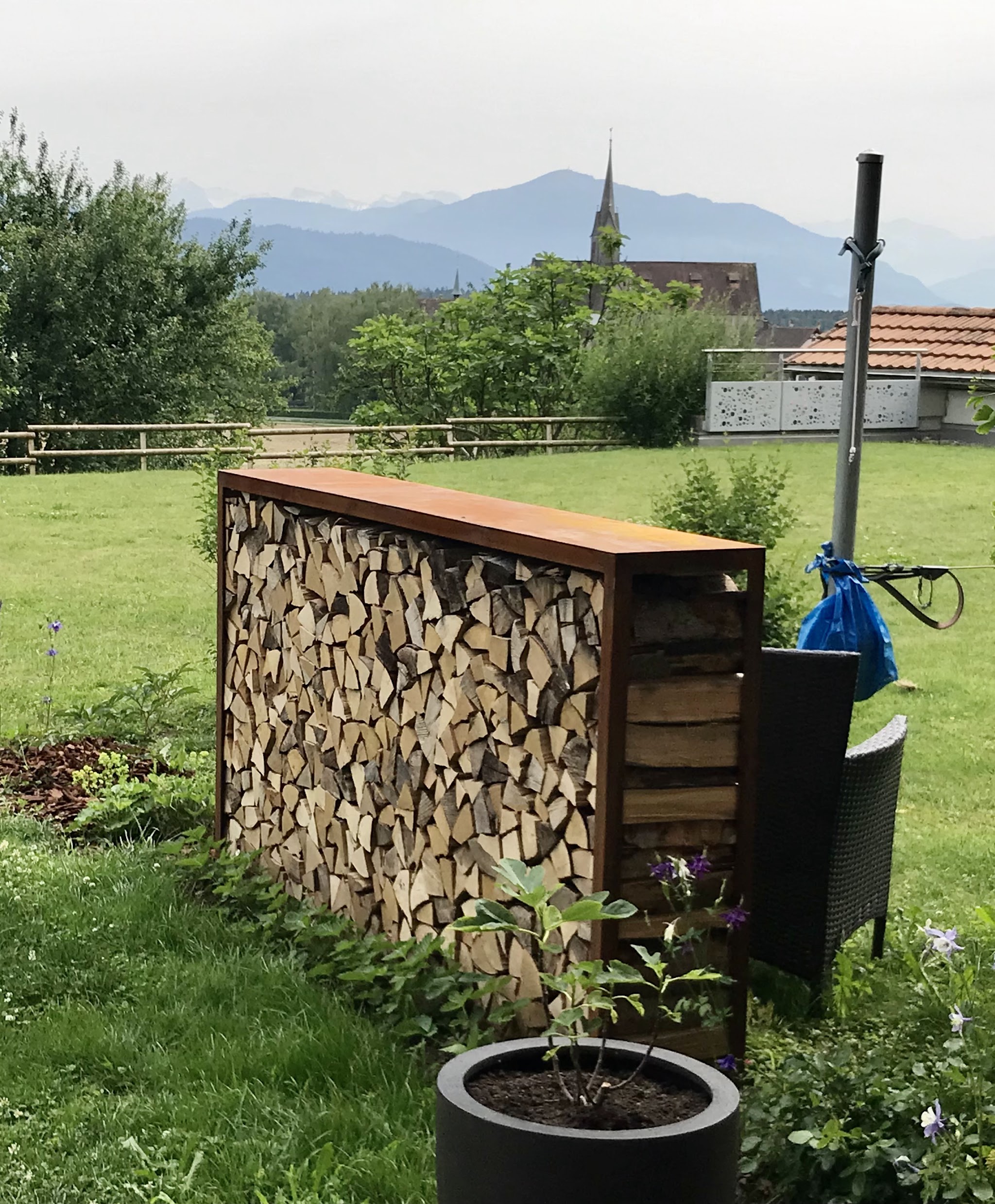Brennholzlager im Garten mit Blick auf die Berge