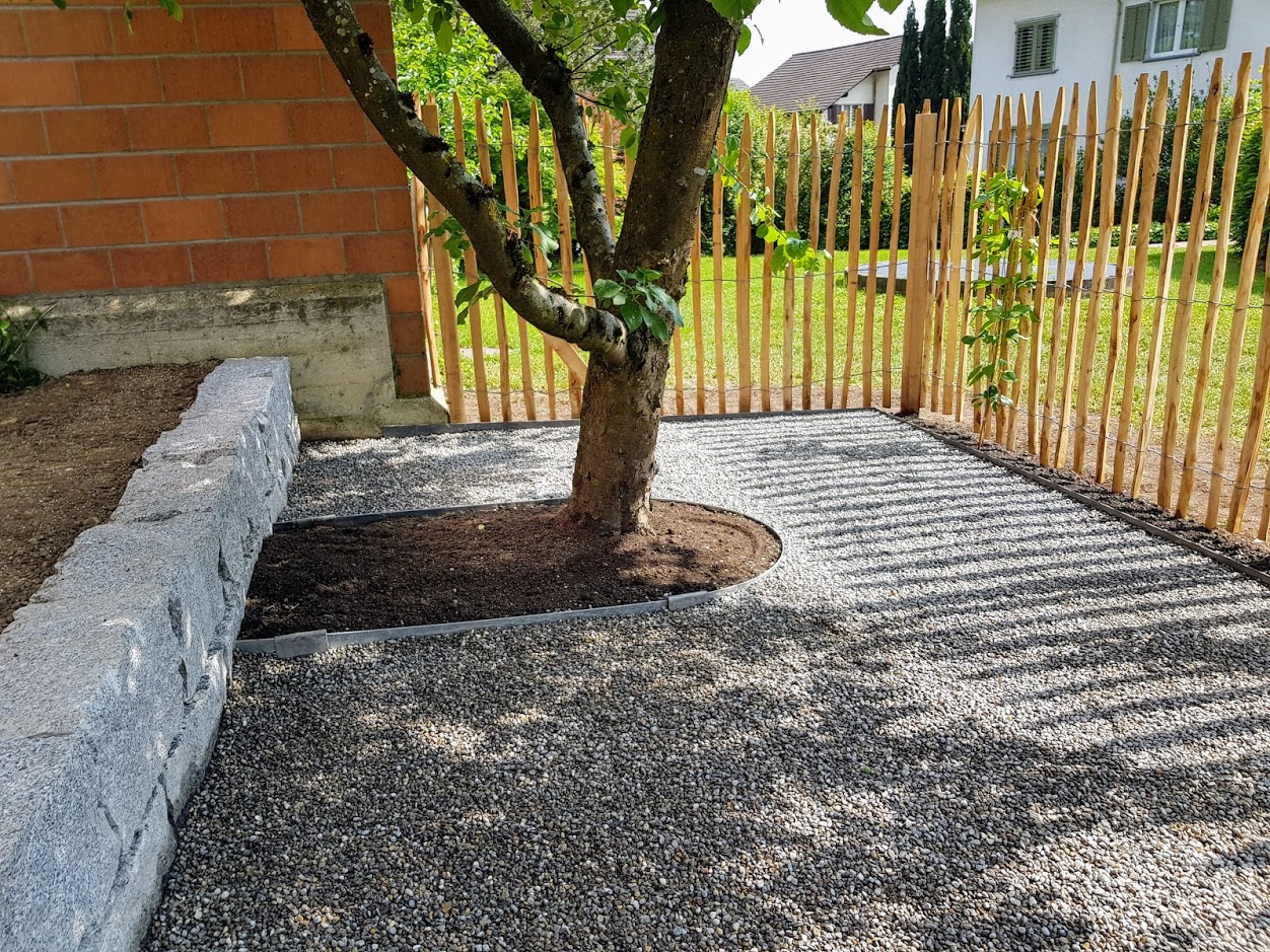Sitzplatz mit Kies und Granitkante unter einem Baum