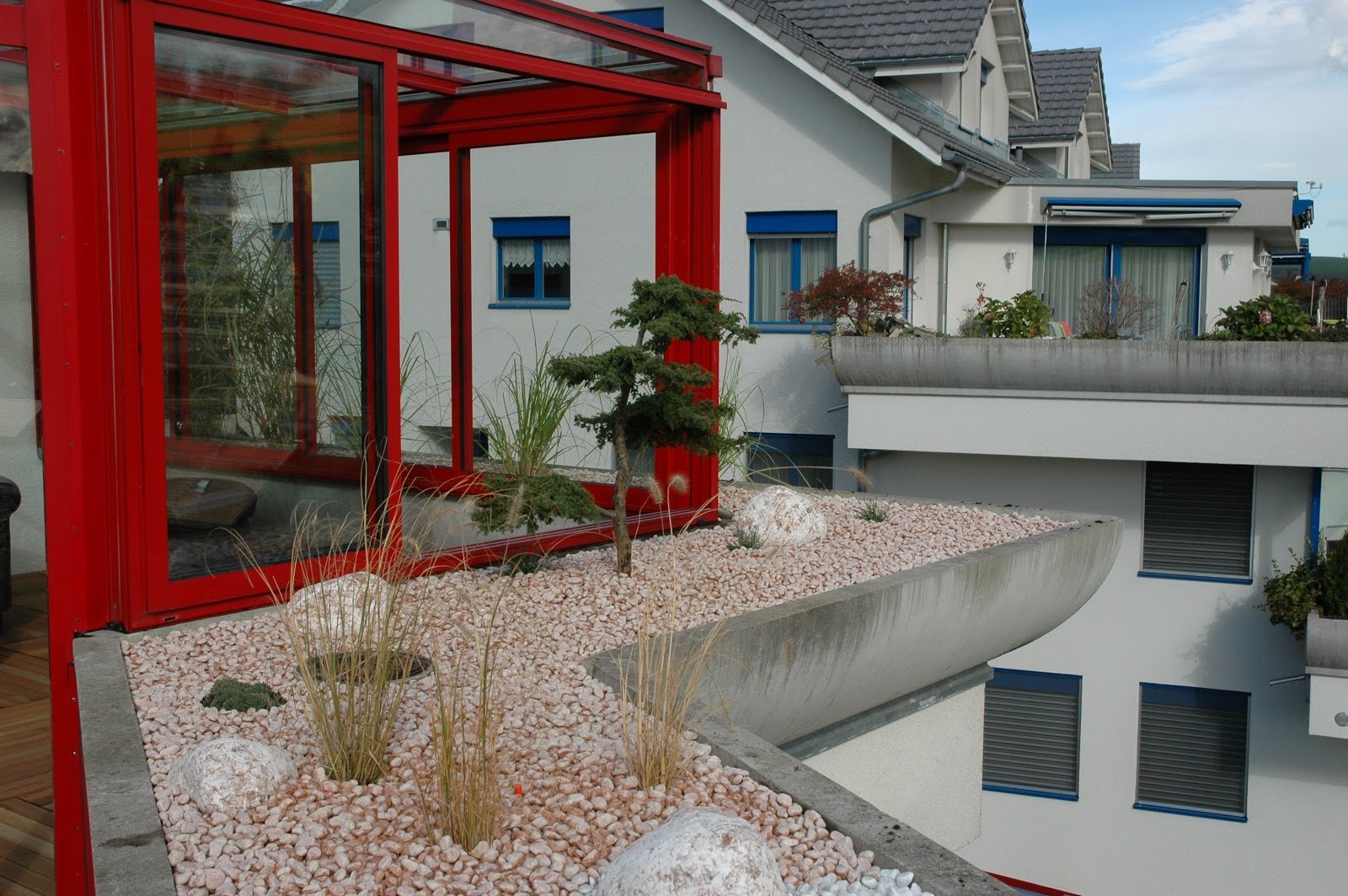 Kiesbeet mit Gräsern vor einem Wintergarten